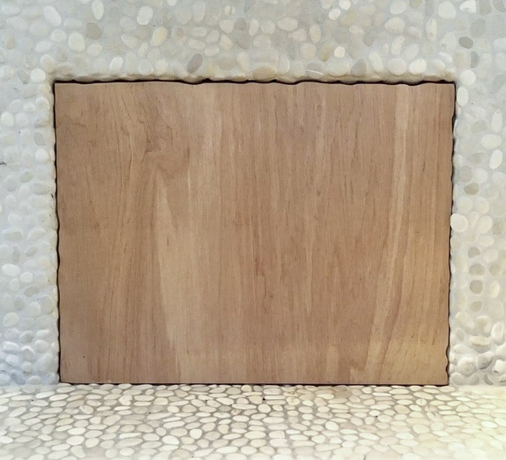 Square piece of plywood sitting as a fireplace insert to block draft