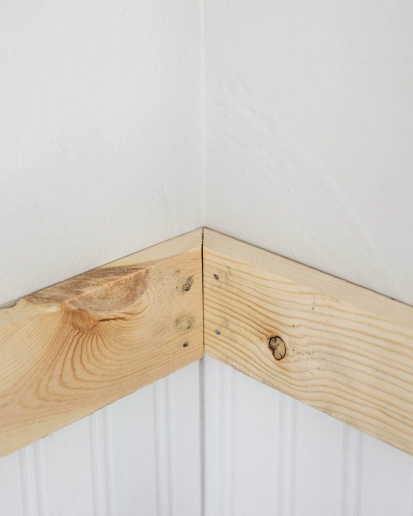 Two boards meeting in a corner with angled cuts and nailed to the wall as trim pieces