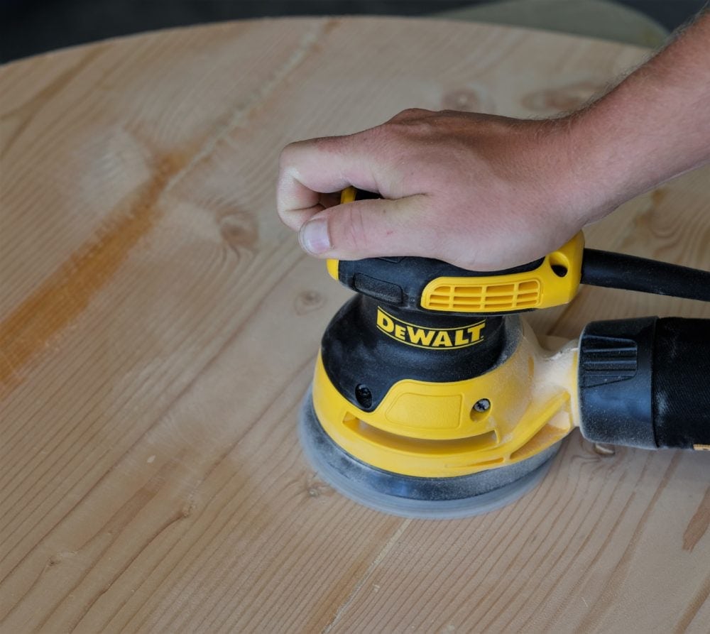 Man sanding rustic coffee table with DeWalt sander