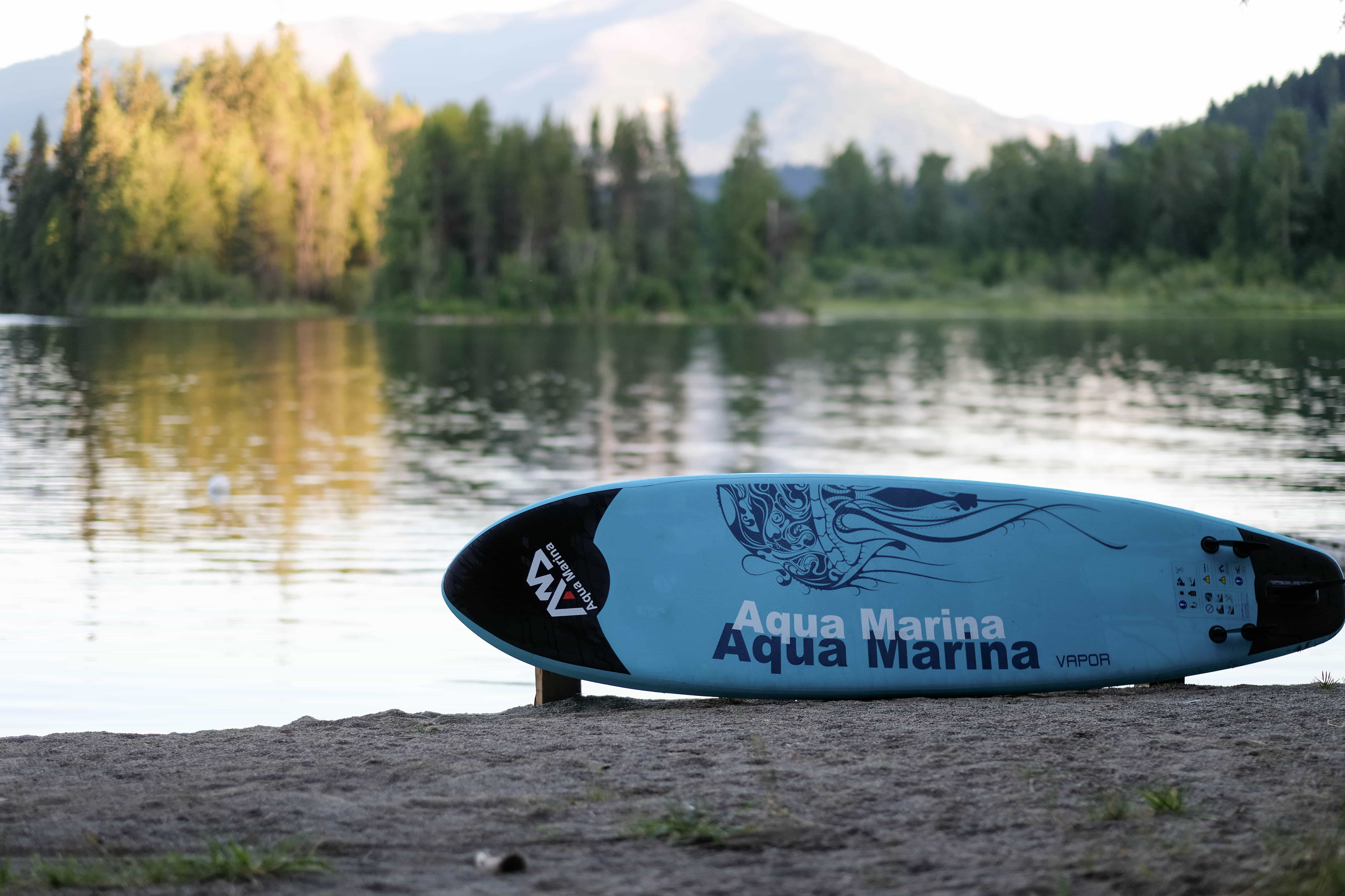 aqua marina VAPOR SUP inflatable SUP sitting on the beach in front of a lake