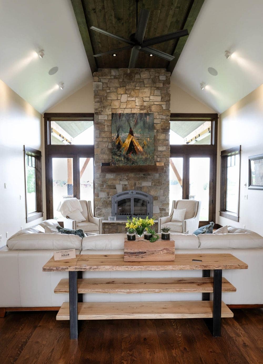 parade of homes living room with white leather couch, fireplace, and large windows