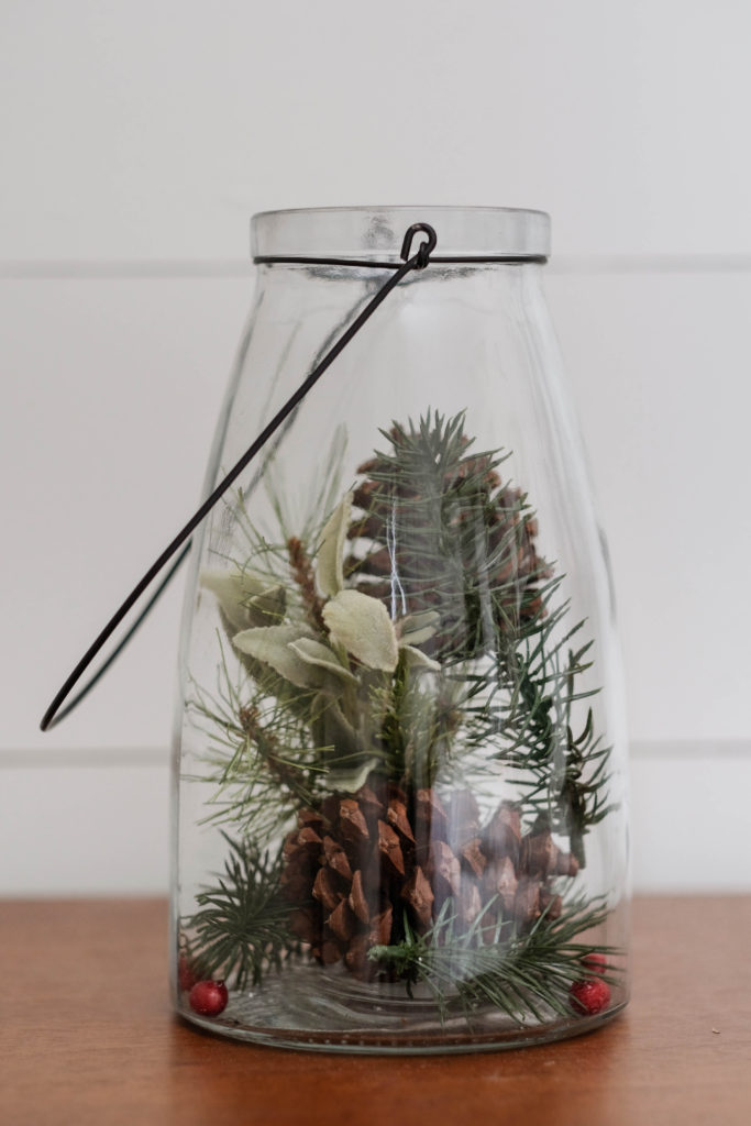 Christmas decor using a glass lantern filled with pinecones and pine tree clippings