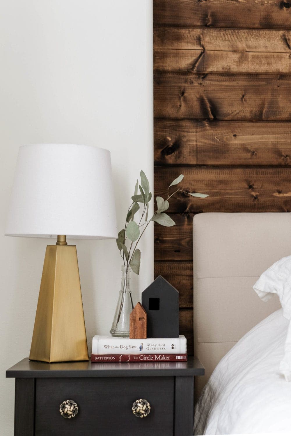 Christmas bedroom decor ideas including a nightstand styled with a gold lamp, books and a plant