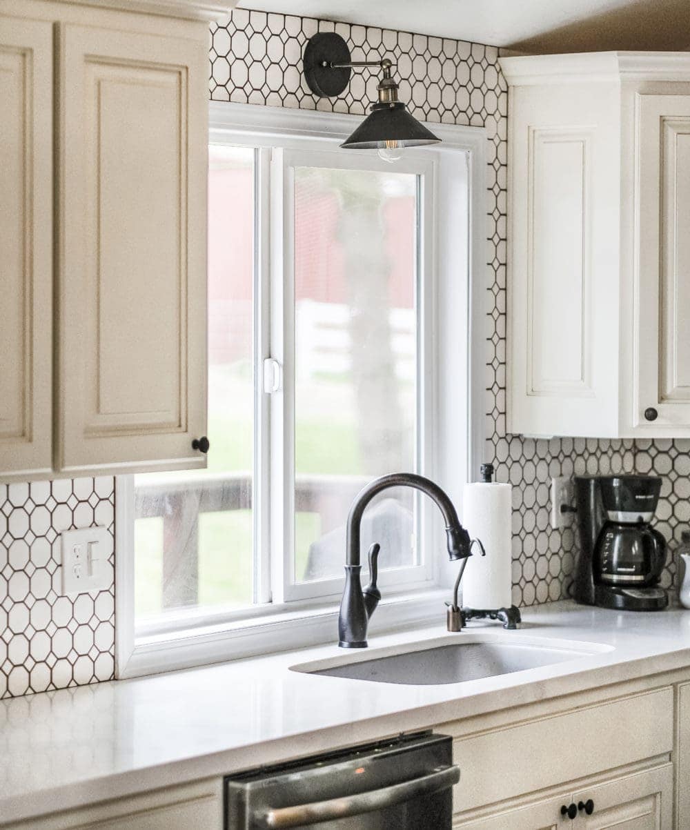 White kitchen with an industrial wall sconce above farmhouse sink