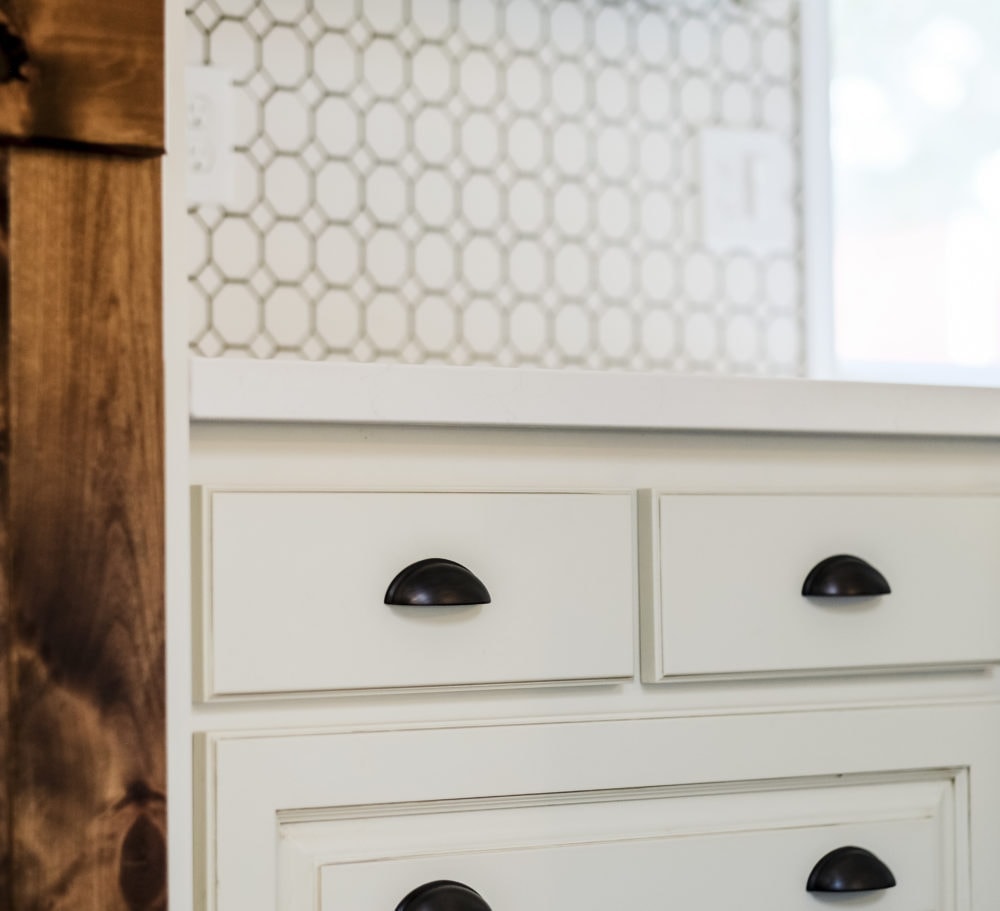 Closeup of oil rubbed bronze cabinet hardware one white drawers for a kitchen on a budget