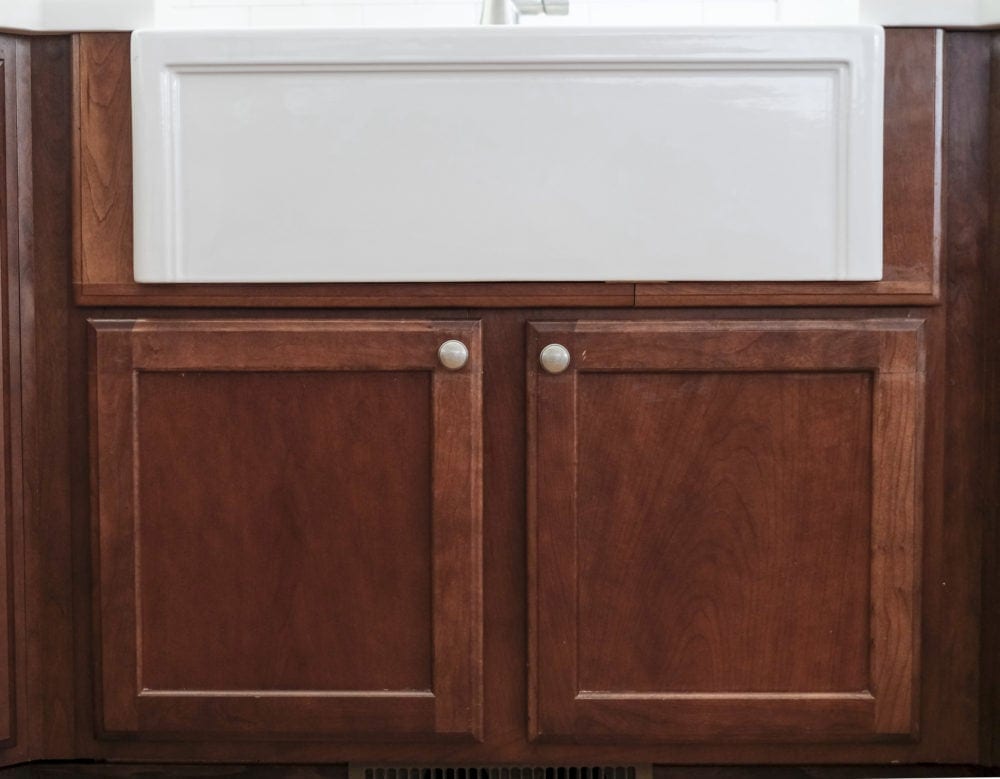 View of white farmhouse sink with custom built cabinet doors below