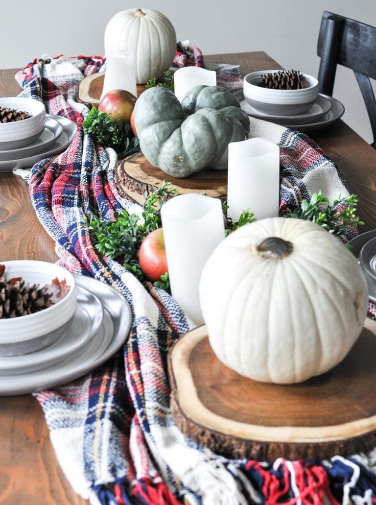 Thanksgiving table centerpieces using a plaid runner, tree slices and white pumpkins