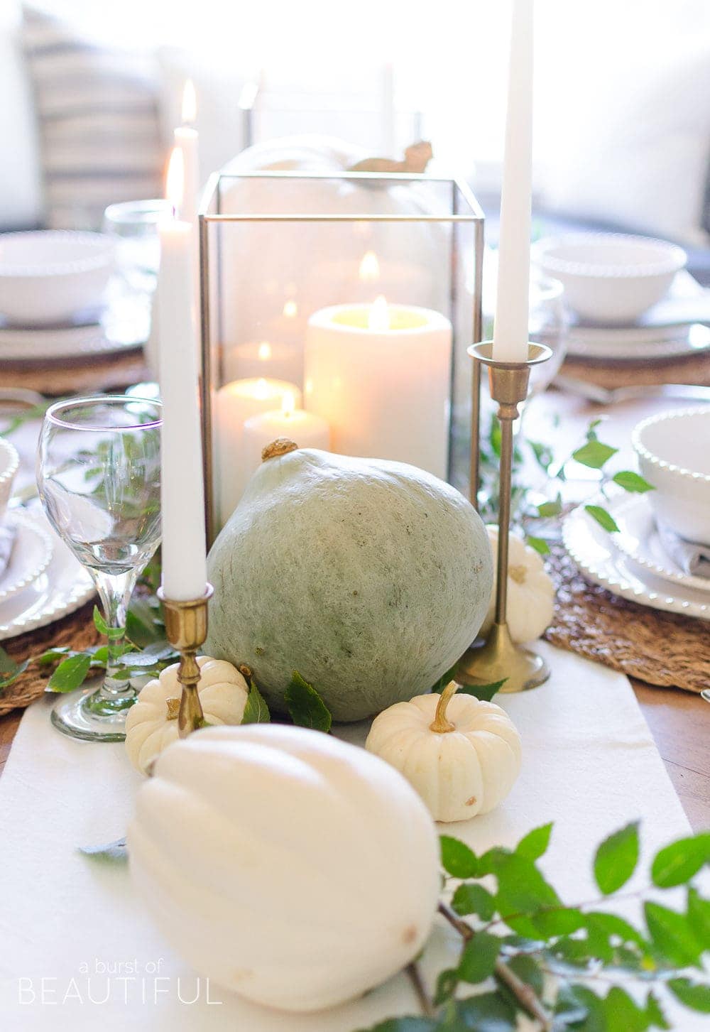 Thanksgiving table centerpieces with neutral colored pumpkins and white candles