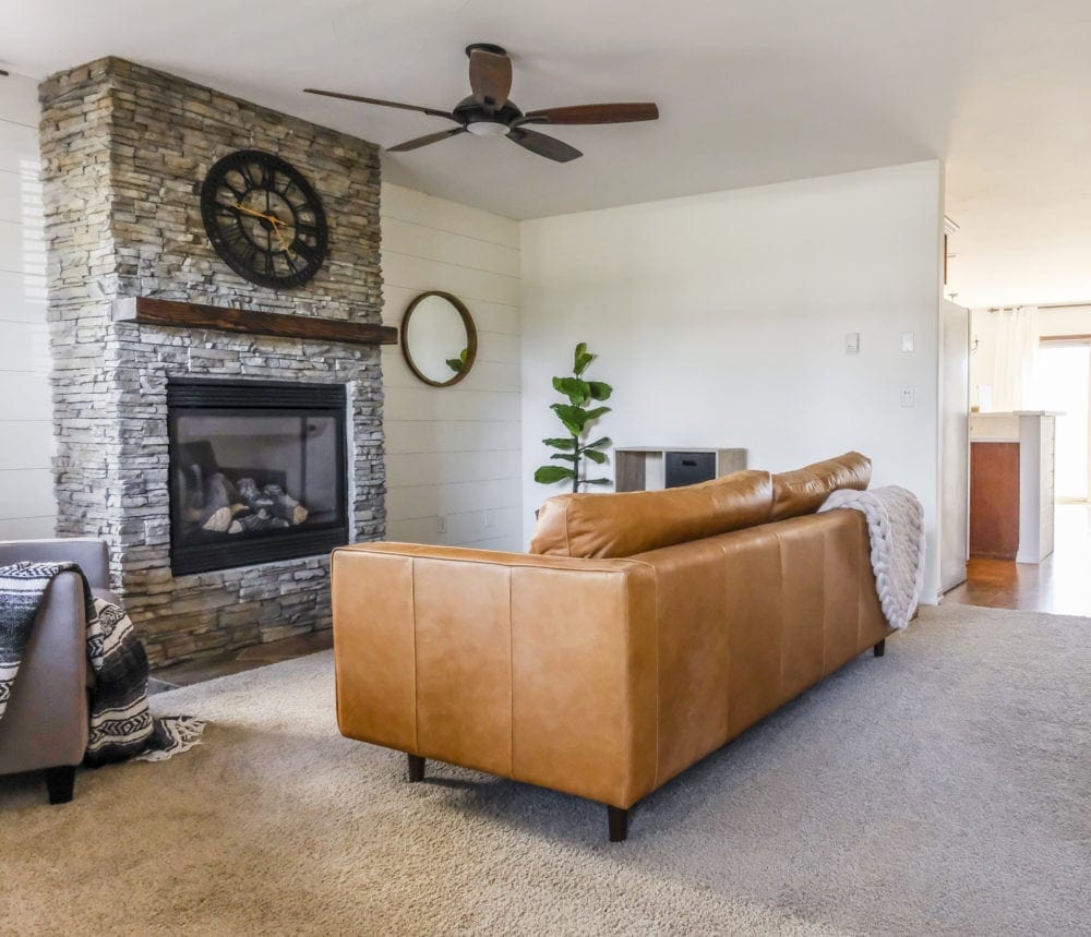 A side view of a leather sofa in a living room in front of a stone fireplace