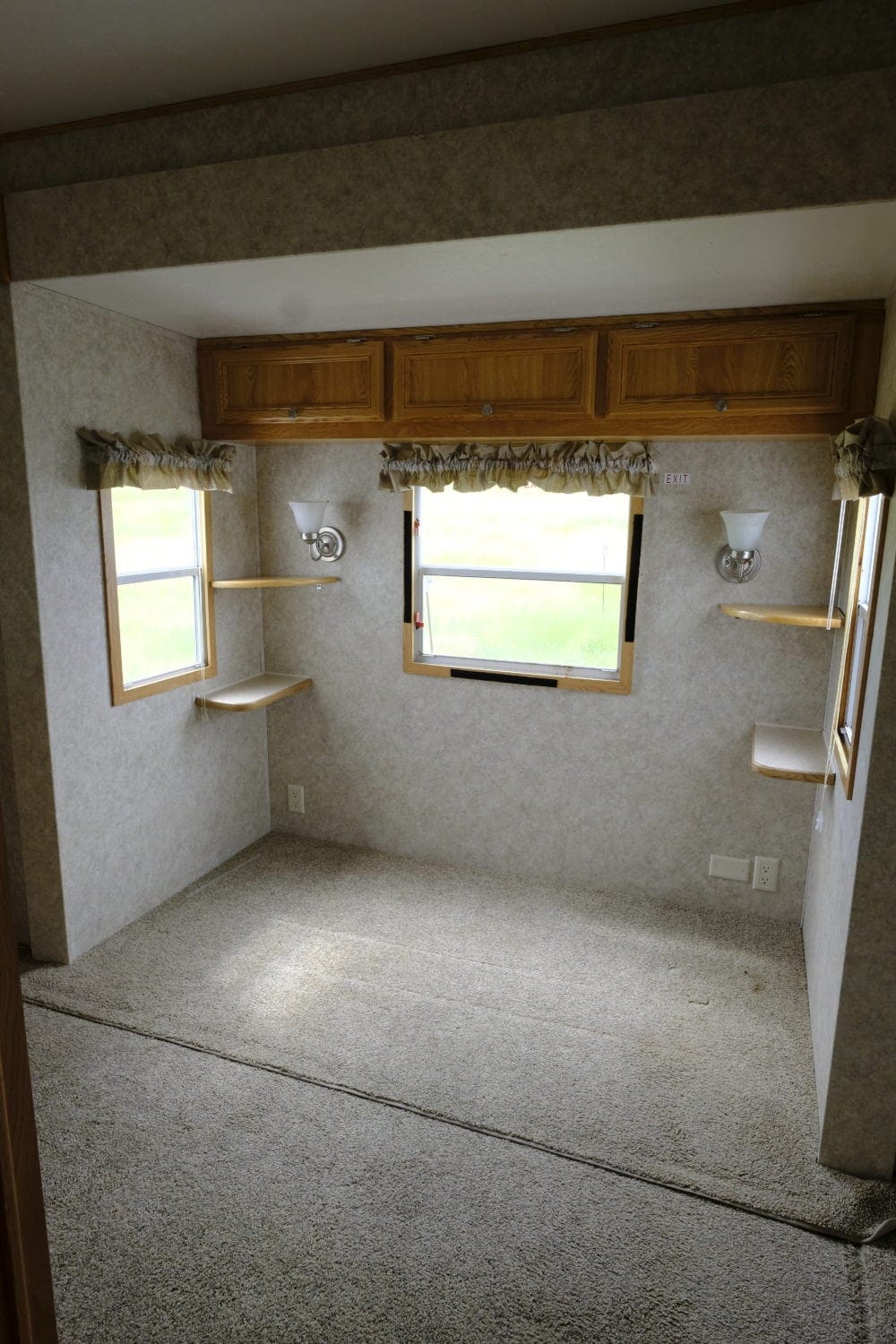 Before photo of a 2005 Damon Bayridge park model RV bedroom with carpet and overhead cabinets