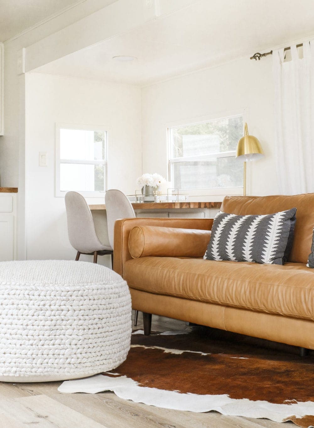 Large pouf in a small room in front of a brown leather couch