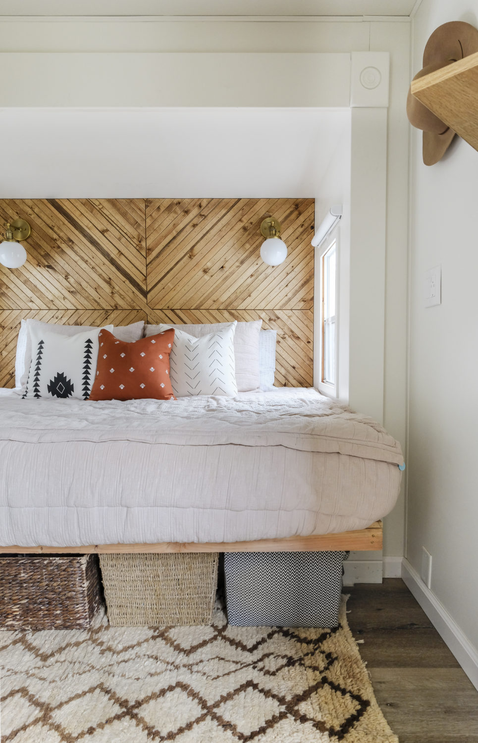 RV bedroom with bed inside popout and baskets under the bed