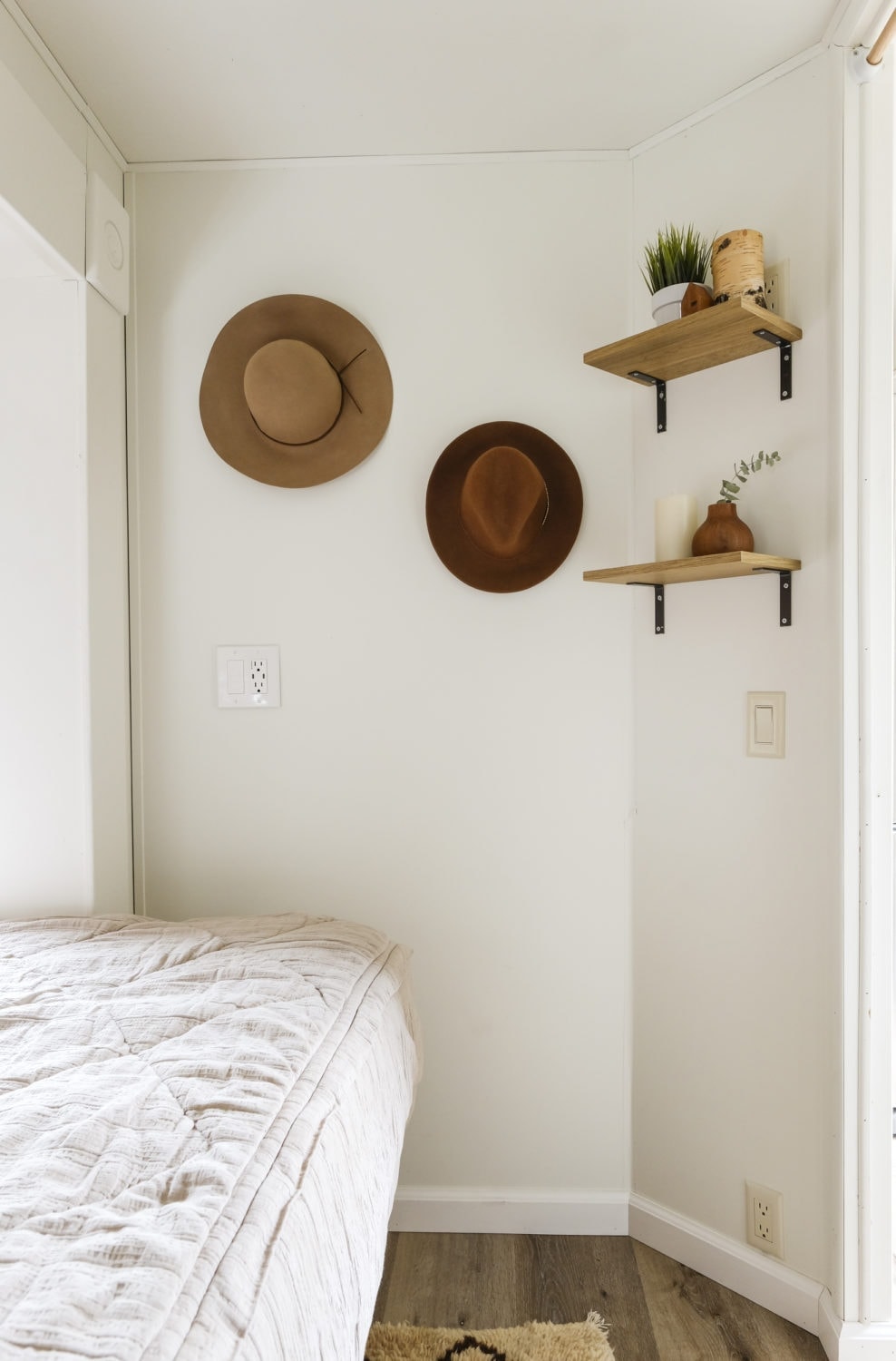 RV bedroom remodel with hats hanging on the wall and open shelving