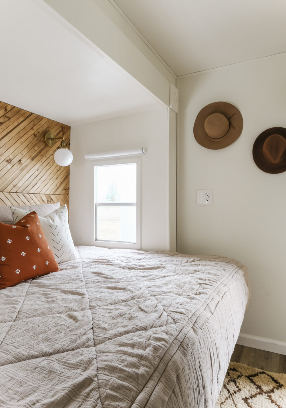 RV bed with zippered bedding and hats on the wall