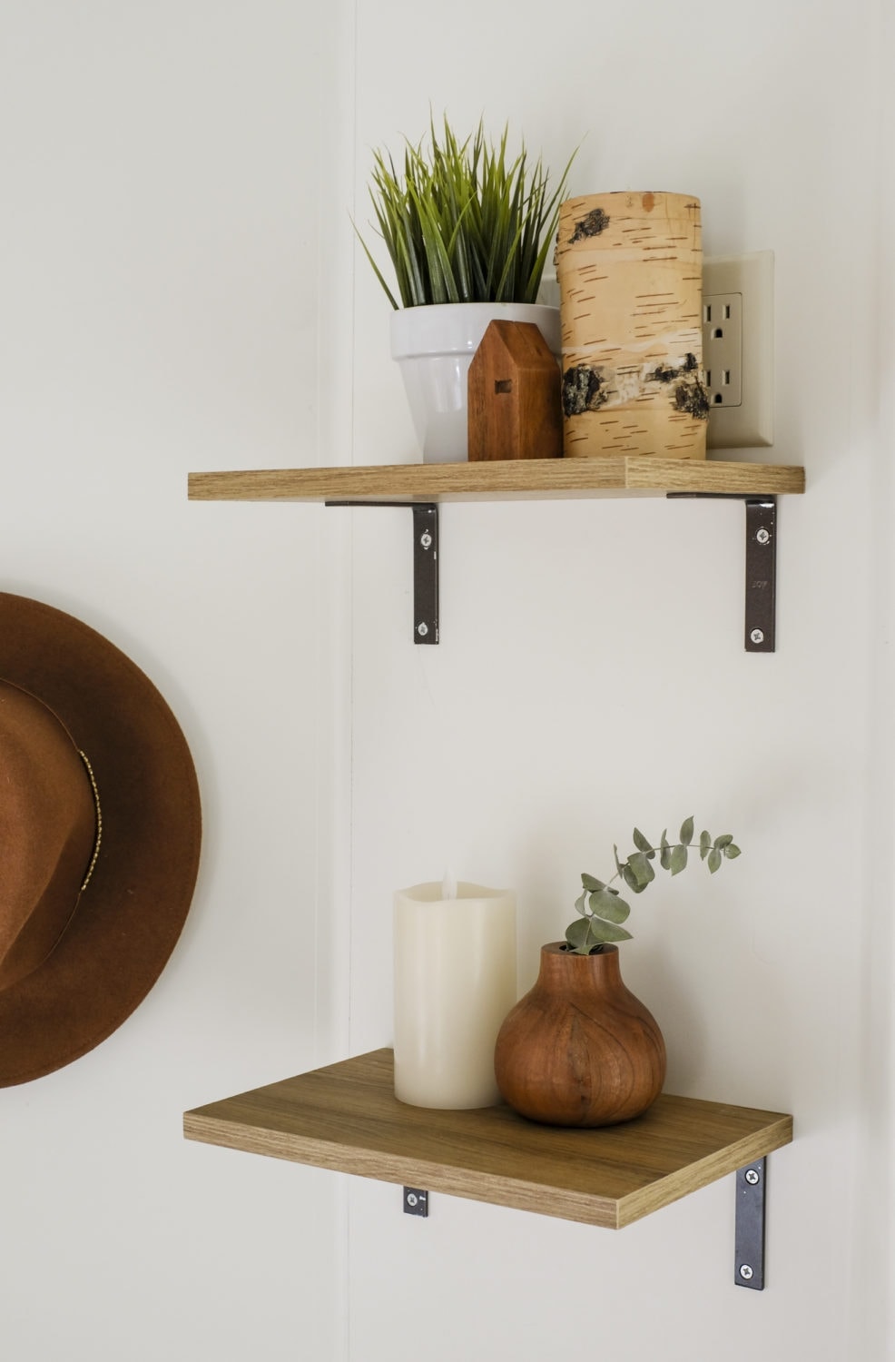 Two open shelves with candles and greenery on top