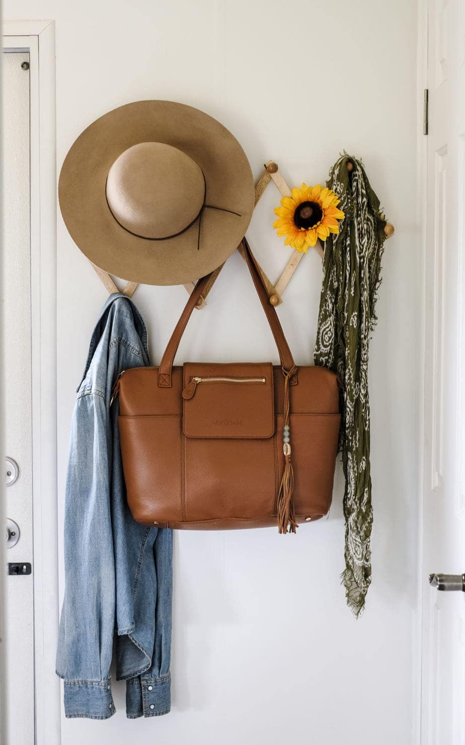 leather diaper bag hanging on coat rack