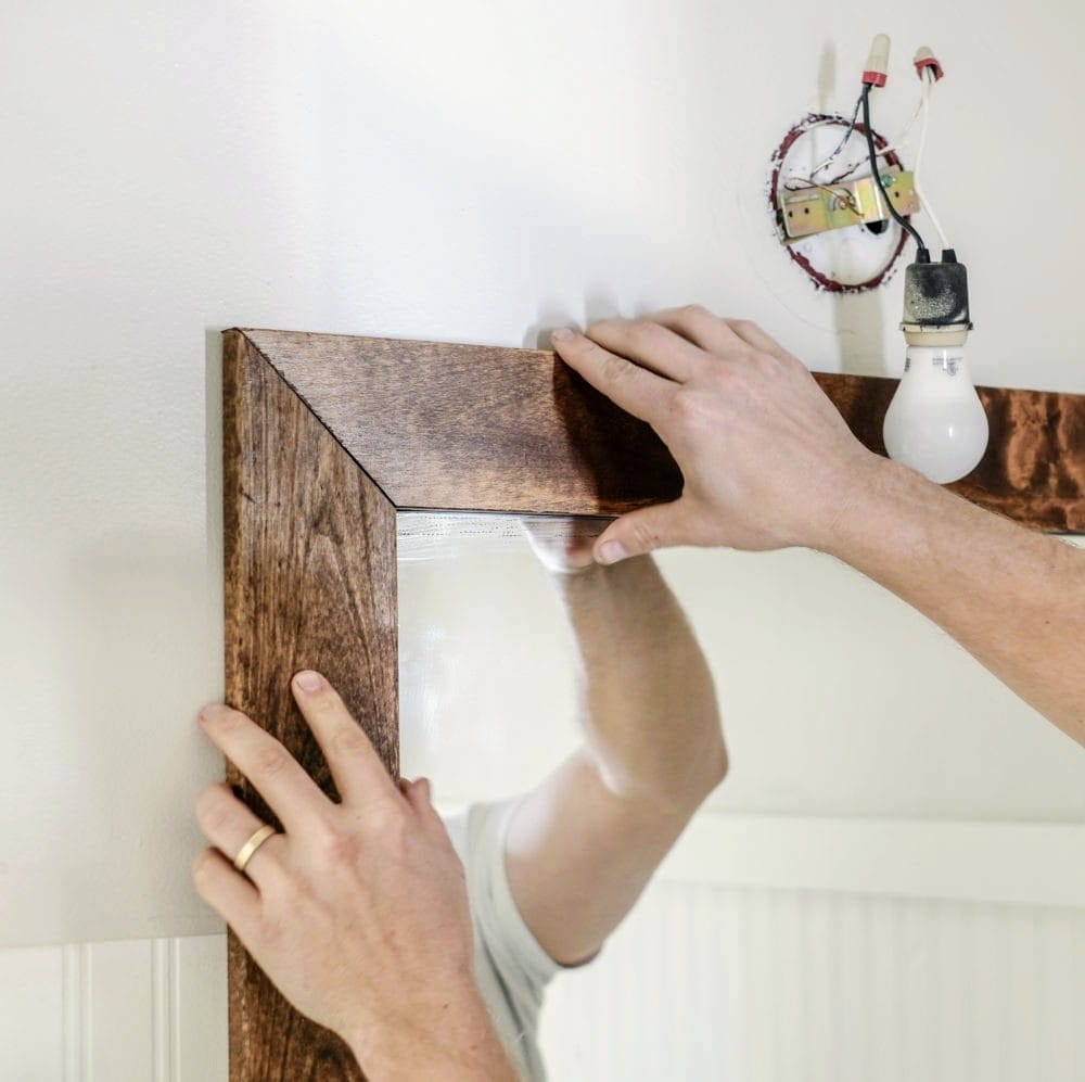 installing wood boards onto the wall around a bathroom mirror 