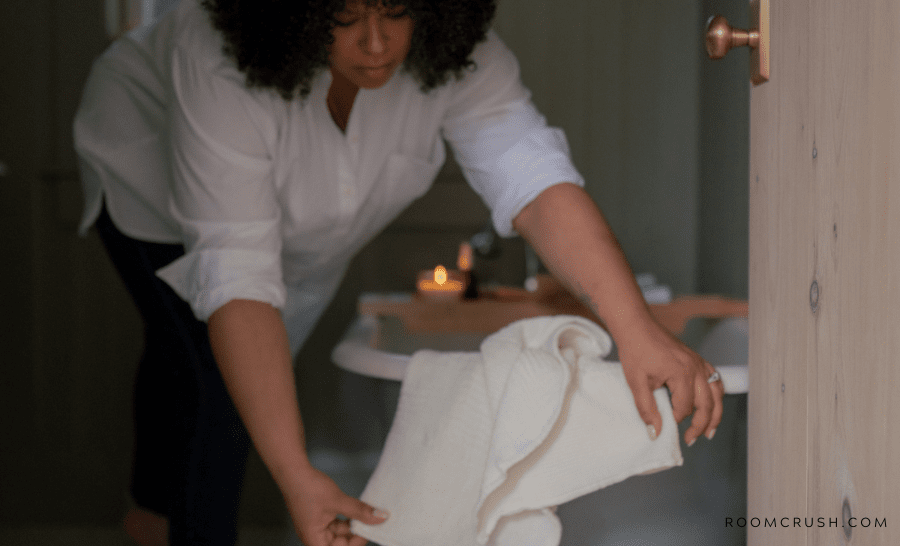 Woman tidying up her bathroom with a towel showing the best bathroom cleaning hacks