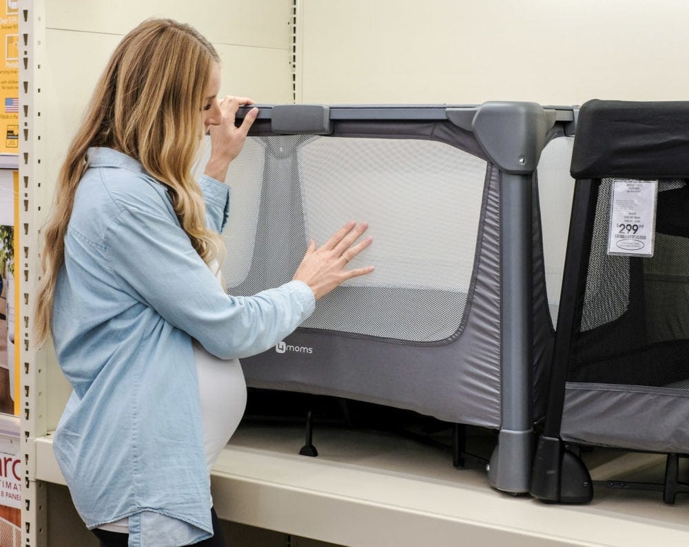 blonde woman looking at baby play pen with buybuybaby price match promise