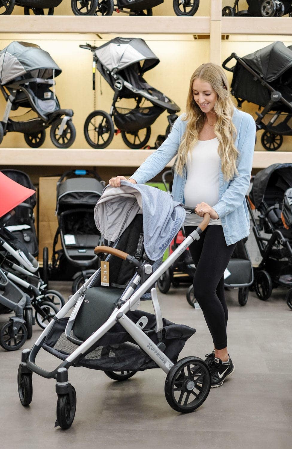 blonde woman testing out stroller in store at buy buy baby