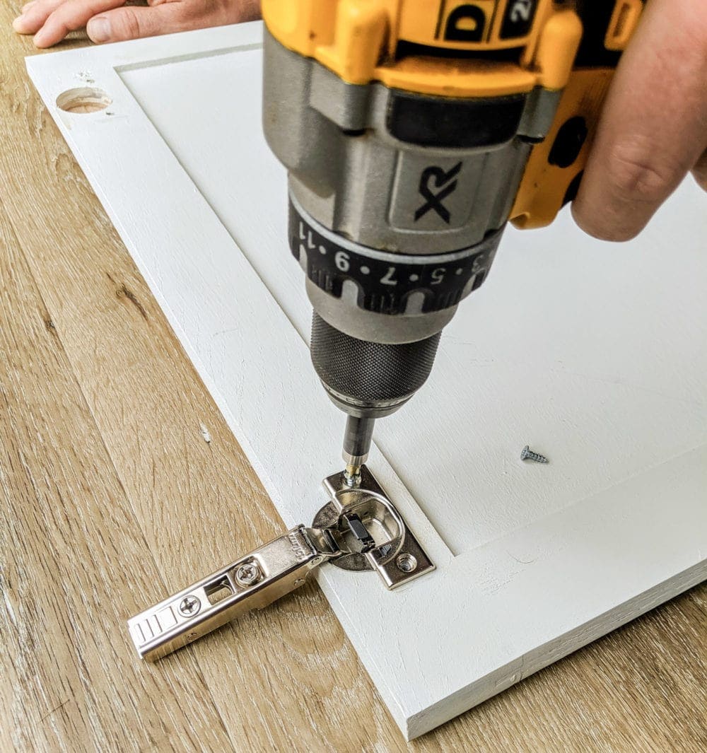 screwing a soft close hinge into a cabinet door