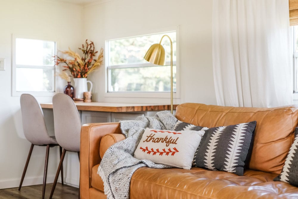 couch decorated for fall with throw pillows and a wool blanket