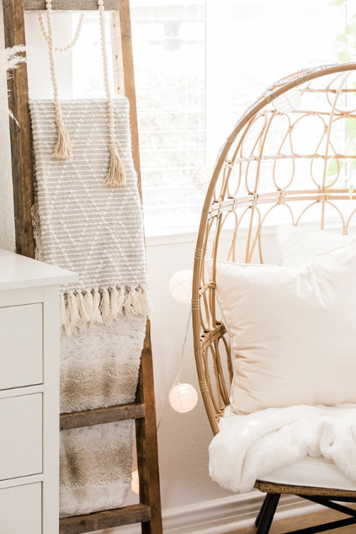 Learn How to Create a Modern Bohemian Home decor tips. Photo is of a modern bohemian home with a rattan chair in a bedroom and beige cushions.