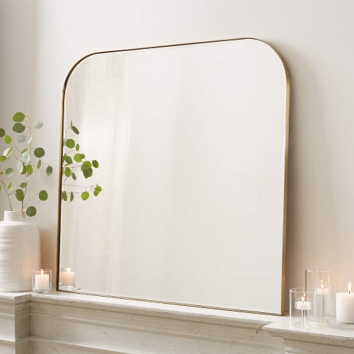 Arched mirror showing how to decorate a mantel