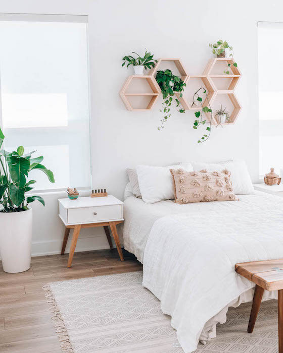 a bedroom with plants and greenery hanging on the wall above the bed