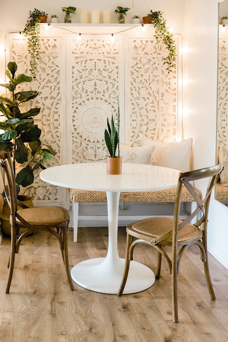 Dining room in a modern bohemian home with fairy lights, plants and 70s decor.