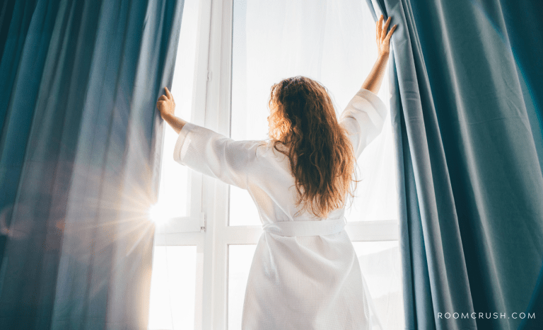 Woman opening curtains, learning How To Hang Curtains Without Drilling Holes