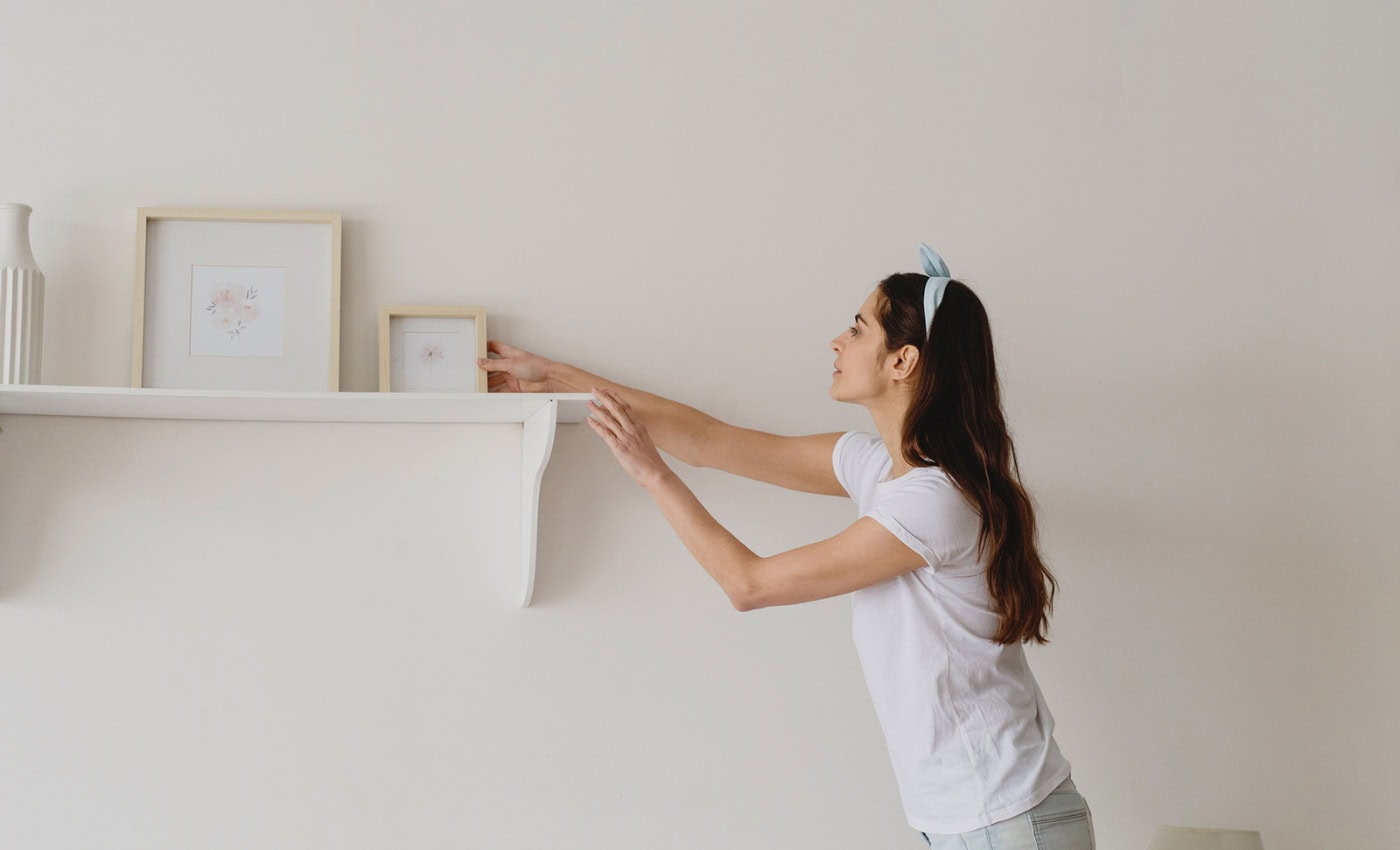 woman reaches for shelf infront of Agreeable Gray by Sherwin-Williams wall