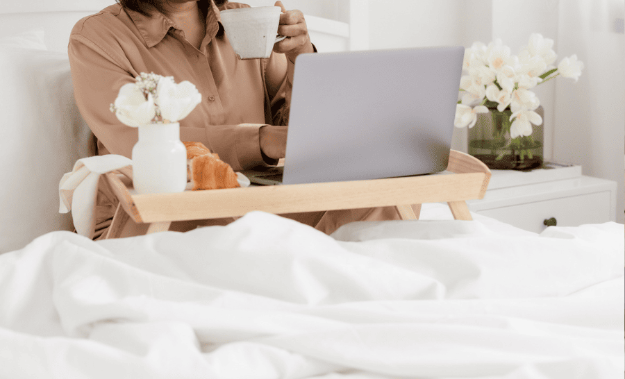 woman sits in her cozy bed sipping a coffee as she learnsabout the 9 Best Organic Duvet Covers For Sustainable Coziness
